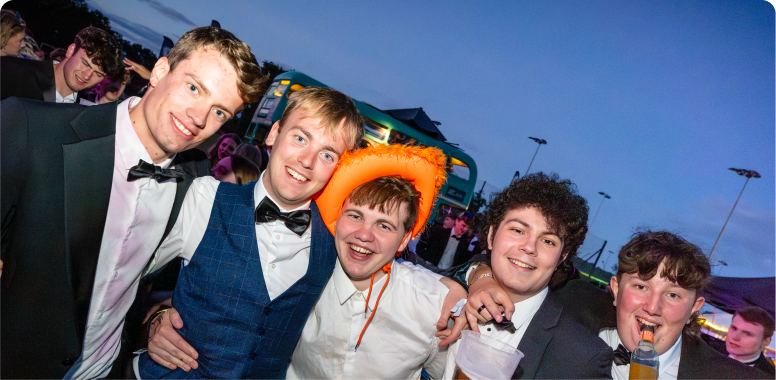 Students smiling with suits on a cowboy hat at the Barn