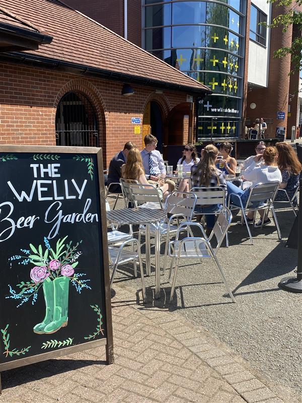 Outside of the Welly Inn with a group round a table enjoying the sunshine